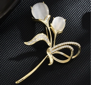 Détail de la broche tulipe en métal doré, pierres œil de chat blanches et zircons
