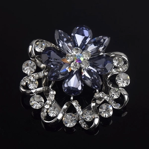 Macro detail of crystal flower brooch with blue pear-cut petals and silver metal accents