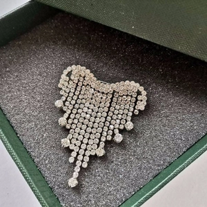 Eleganter glitzernder Herz-Brosche mit Straßquasten in einer grünen Schmuckschatulle