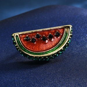 Macro shot of watermelon brooch with red glaze, black rhinestones, and gold metal trim