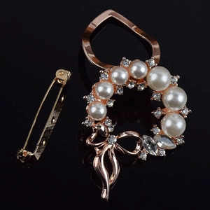 Detailed macro view of a rose gold floral wreath brooch with white pearls and crystals