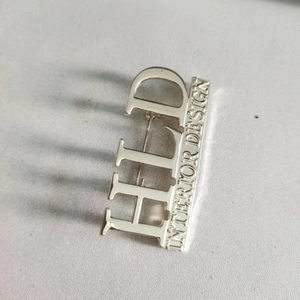 Detailed close-up of polished silver alphabet brooch featuring vertical HLD lettering