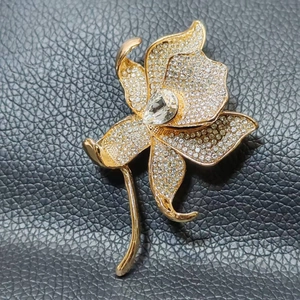 Detail view of gold lily brooch with white crystals and a pear-shaped center diamond
