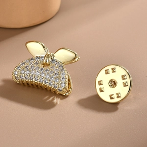 Elegant gold butterfly brooch with shimmering white rhinestones on soft beige background