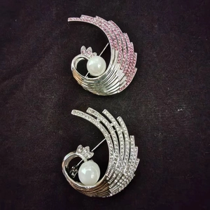 Detailed close-up of a phoenix wing brooch with cubic zirconia and a central white pearl
