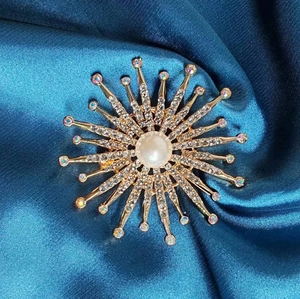 Broche tournesol dorée élégante avec cristaux et perle centrale sur tissu en soie