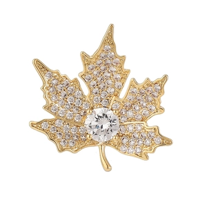 Golden maple leaf brooch with sparkling white cubic zirconia pavé on a white background