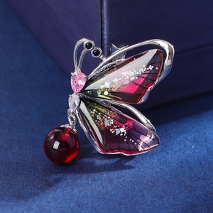 Broche papillon argentée avec ailes dégradées violettes et perle rouge pendante élégante