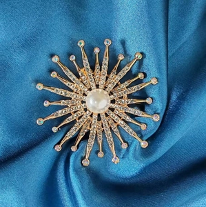 Détail d'une broche tournesol avec perle blanche, placage à l'or et cristaux brillants