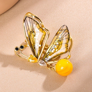 Élégante broche papillon dorée avec ailes ambrées translucides et pendentif à pampilles