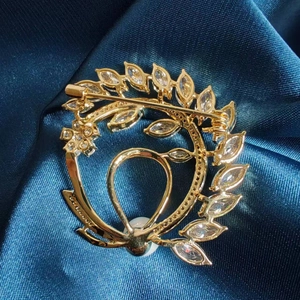 Detail view of gold vintage leaf brooch with zircon marquise stones and pearl on silk