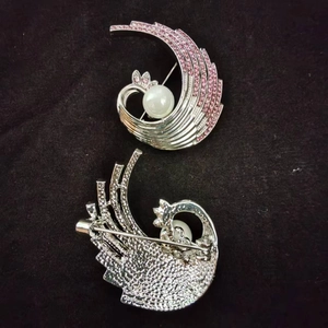 Macro detail of phoenix brooch front and back with pink crystals and a white pearl