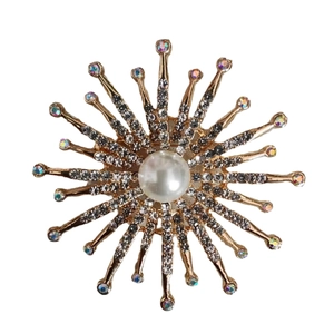 Broche soleil dorée élégante avec grande perle blanche et cristaux scintillants sur fond blanc