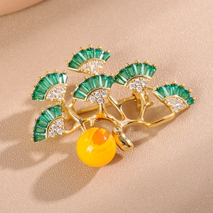 Close-up of golden ginkgo leaf brooch with green zircons and a yellow pearl detail