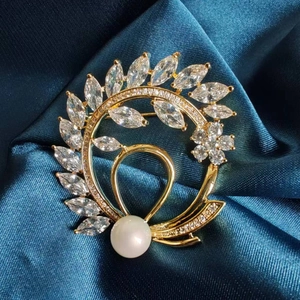 Detailed view of floral wreath brooch with marquise zircons and white pearl on blue silk