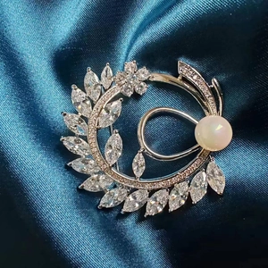 Macro shot of a floral wreath brooch with silver leaves, quartz flower, and white pearl