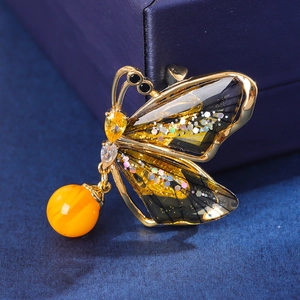 Macro de la broche papillon avec placage doré, zircons étincelants et détail de perle jaune