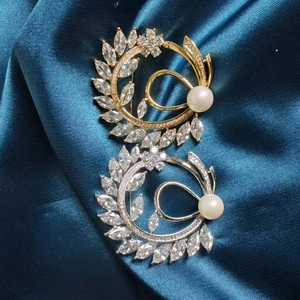 Detailed view of silver and gold crescent moon flower brooches with pearls on blue silk