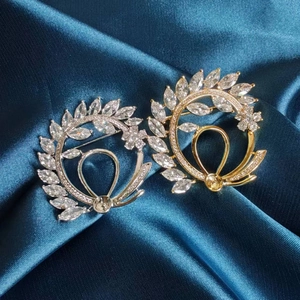 Detail of luxury laurel leaf brooches with marquise crystals on dark teal silk fabric