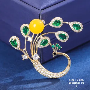 Detailed close-up of emerald peacock brooch with gold plating and white rhinestones