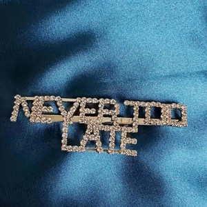 Vue rapprochée de la barrette argentée ornée de strass avec la phrase Never Too Late