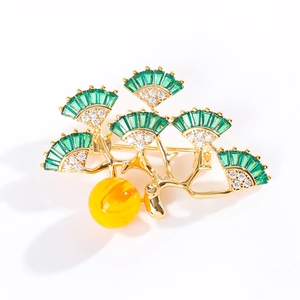 Elegant ginkgo leaf brooch with green zircon and yellow pendant on white background