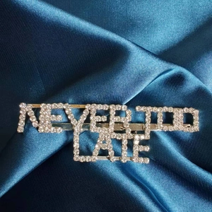 Broche en strass étincelants NEVER TOO LATE sur un élégant fond de satin foncé