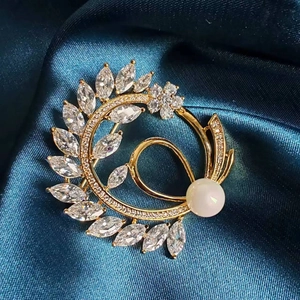 Macro shot of a gold floral brooch with marquise zircons and a white pearl on silk