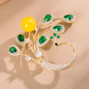 Broche paon élégante avec émeraudes vertes et perle jaune sur une base en métal doré