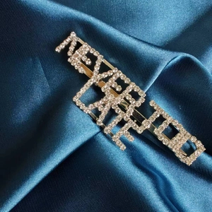 Broche dorée avec strass NEVER TOO LATE sur fond en satin bleu foncé élégant