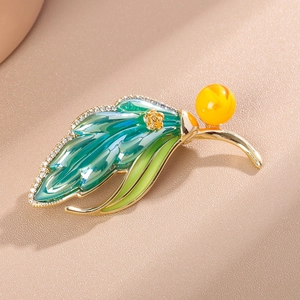 Detailed close-up of leaf brooch featuring green enamel with sparkling zircon stones
