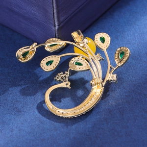 Broche paon dorée raffinée avec gemmes vert émeraude et perle d'ambre sur tissu
