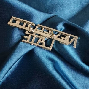 Détail du dos de la broche dorée avec fermoir épingle sur tissu en satin bleu