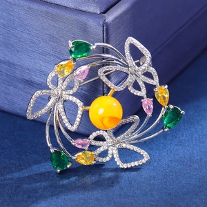 Élégante broche couronne papillon avec pierres colorées et perle sur fond bleu foncé