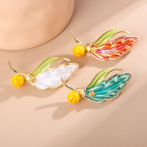 Elegant gold feather brooches with enamel leaf details and sparkling cubic zirconia crystals