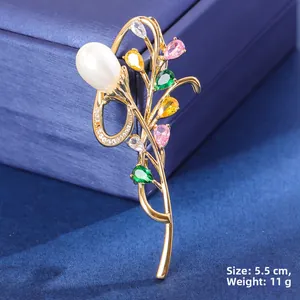 Detail of bouquet brooch with white pearl and colored stones on blue jewelry box