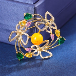 Élégante broche papillon en or avec pierres précieuses et perles sur velours bleu