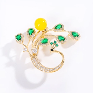 Broche paon élégante en métal doré avec gemmes vertes et perle centrale jaune
