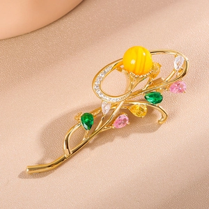 Macro shot of gold floral brooch with yellow amber bead and multi-colored gemstones