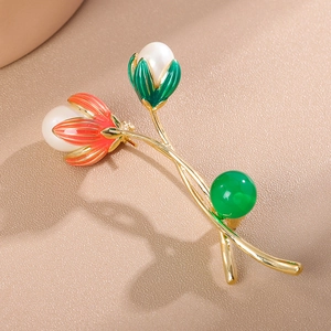 Elegante Tulpenbrosche mit Goldrahmen, Perlen und roter Emaille auf Lederhintergrund