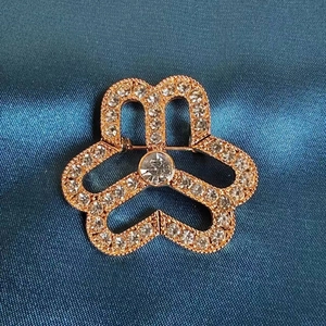 Elegant rose gold floral brooch with pavé rhinestones on dark blue satin fabric