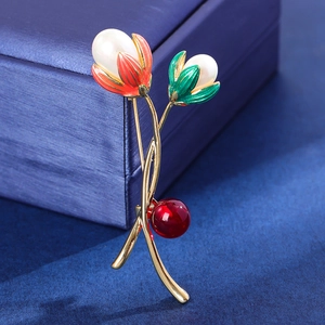 Elegante goldene Tulpenbrosche mit Emaille-Blüten und Perlen auf einer blauen Schmuckdose