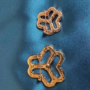 Close-up of rose gold floral brooches with pin backing on dark blue satin fabric