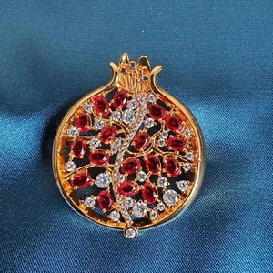 Detailansicht der Granatapfel-Brosche mit roten Zirkonsteinen und goldenem Metallrahmen