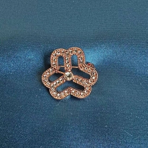 Elegant rose gold round brooch featuring a floral rhinestone design on blue fabric