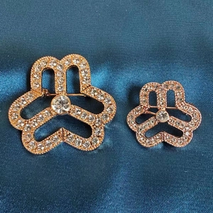 Detailed macro view of rose gold heart-shaped brooches with sparkling white crystals