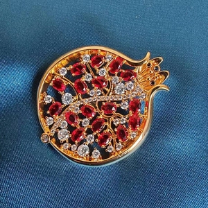 Detailaufnahme der Granatapfel-Brosche mit roten Zirkonia und Goldlegierung