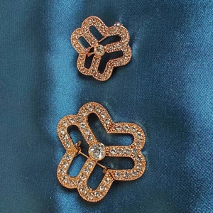 Luxurious rose gold flower brooch with sparkling rhinestones on dark satin background