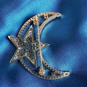 Broche céleste dorée élégante avec zircon lune et étoile sur fond de satin bleu clair