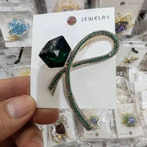 Exquisite ribbon bow brooch with dark green crystal on a white jewelry card